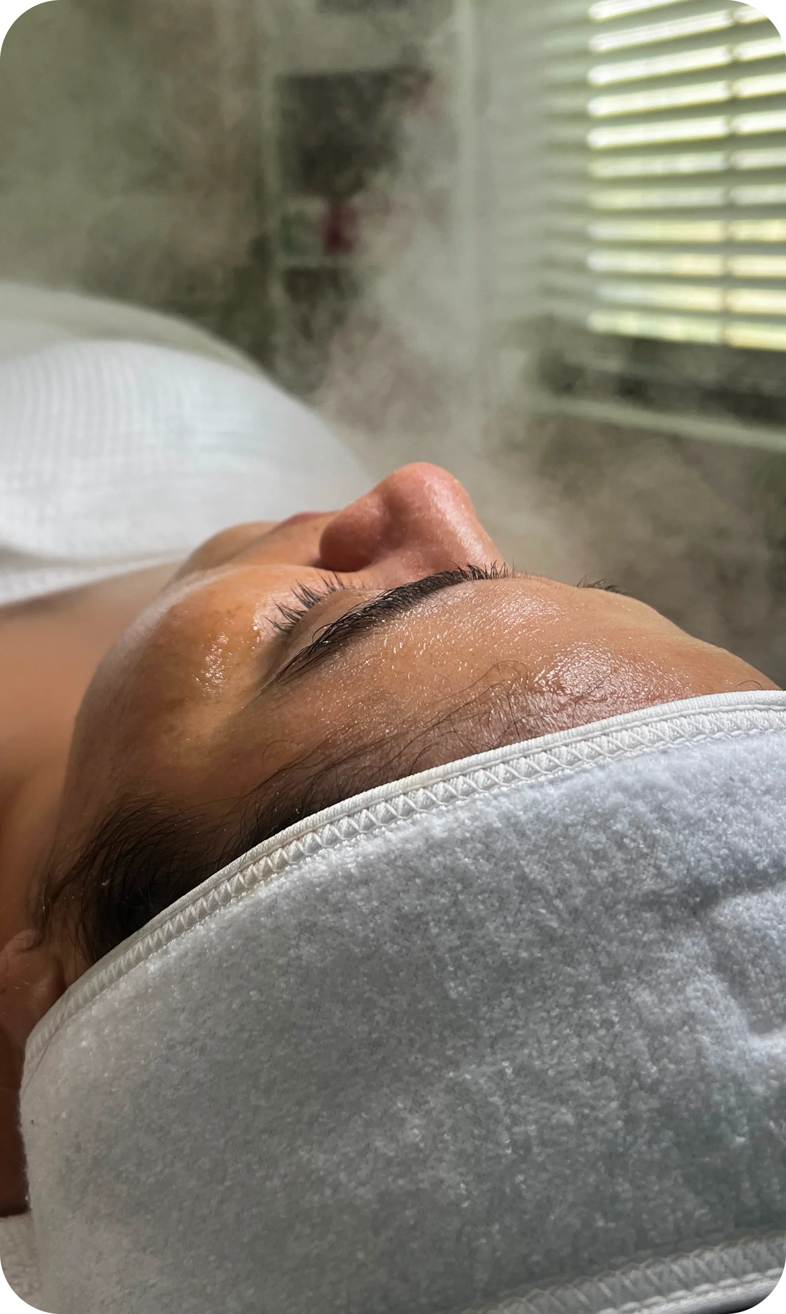 A client lying back under facial steam in the treatment room.
