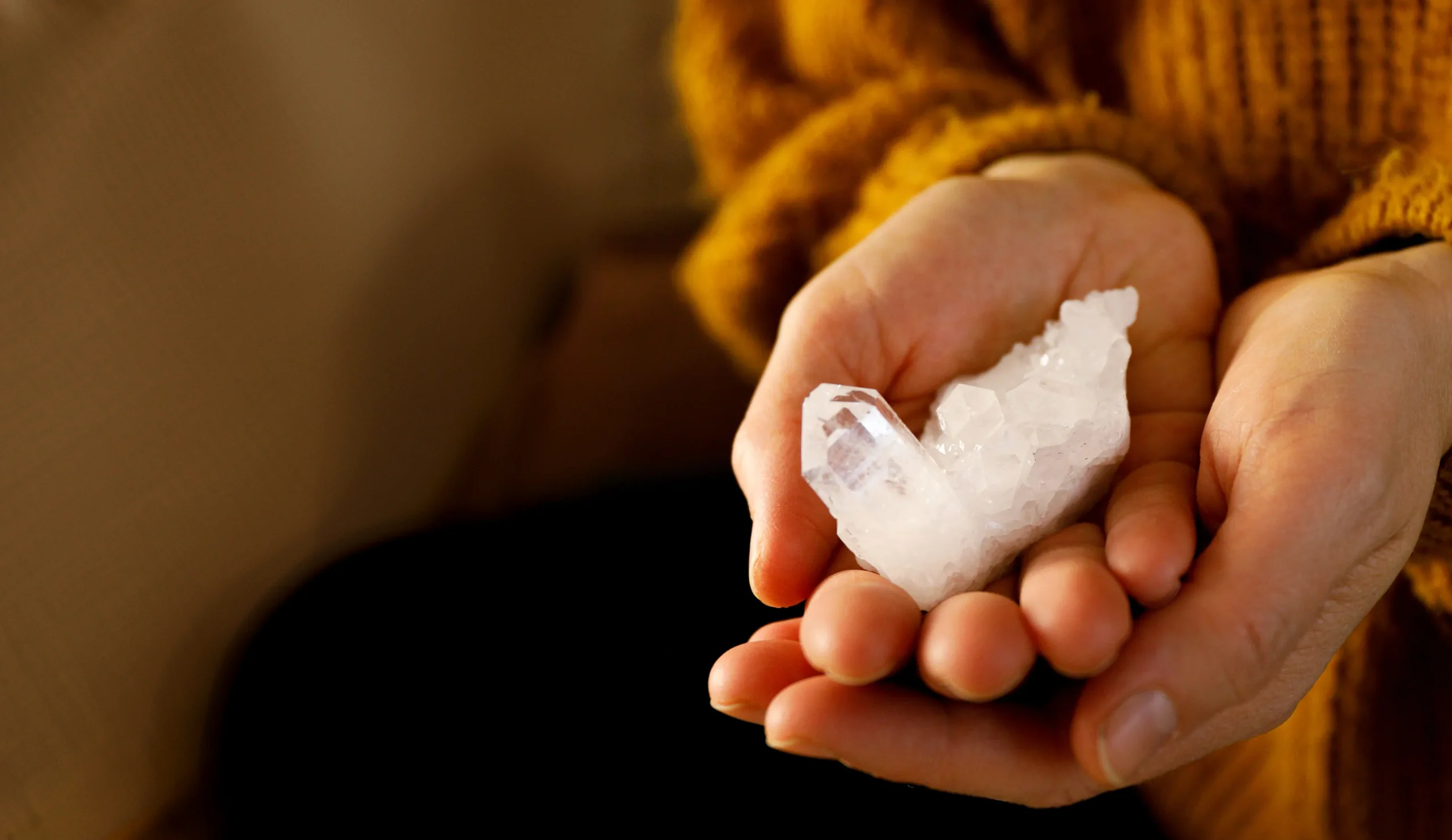 Hands holding a white quartz crystal.