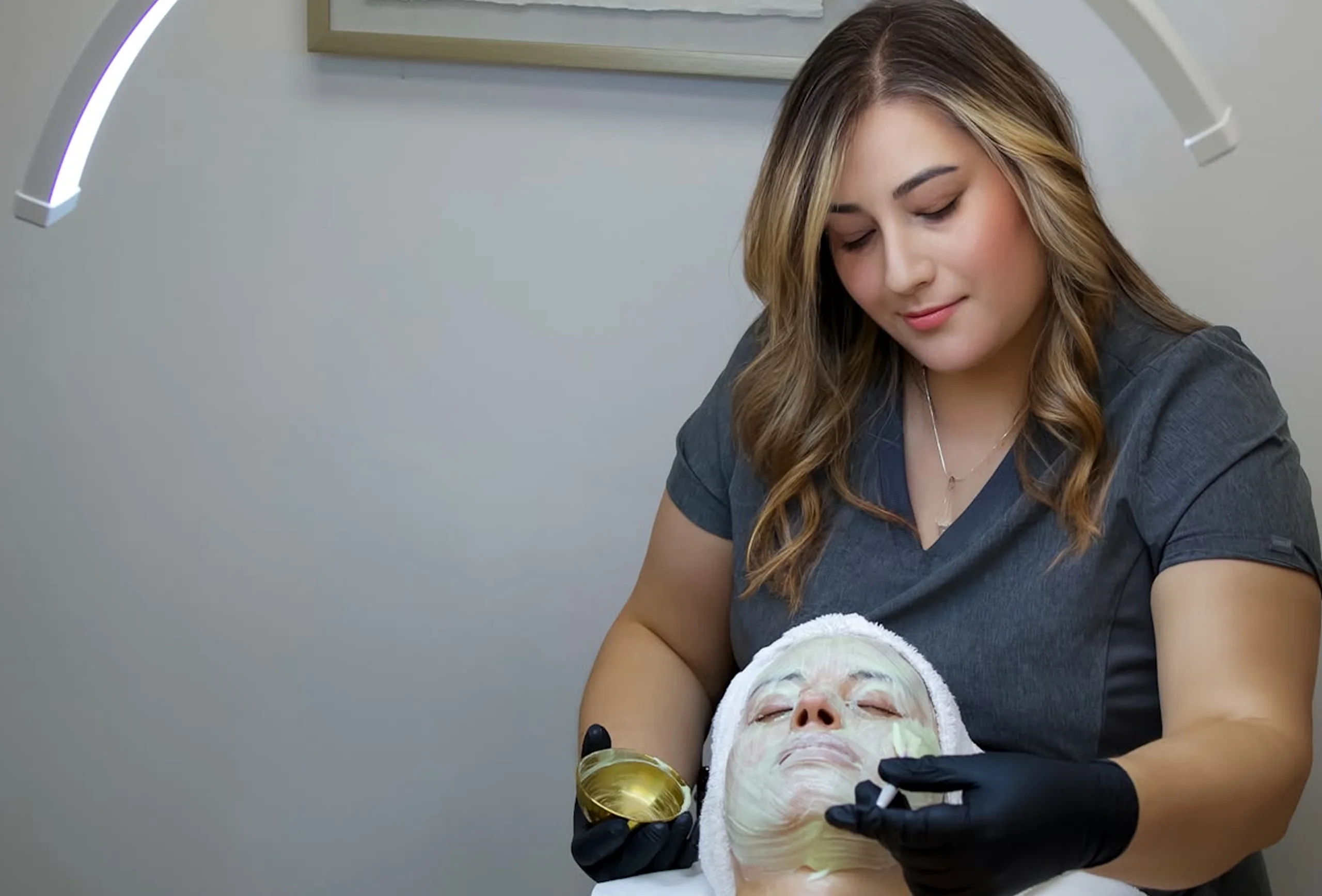 Paola applying a facial mask to a client in the Agapy Studio treatment room.