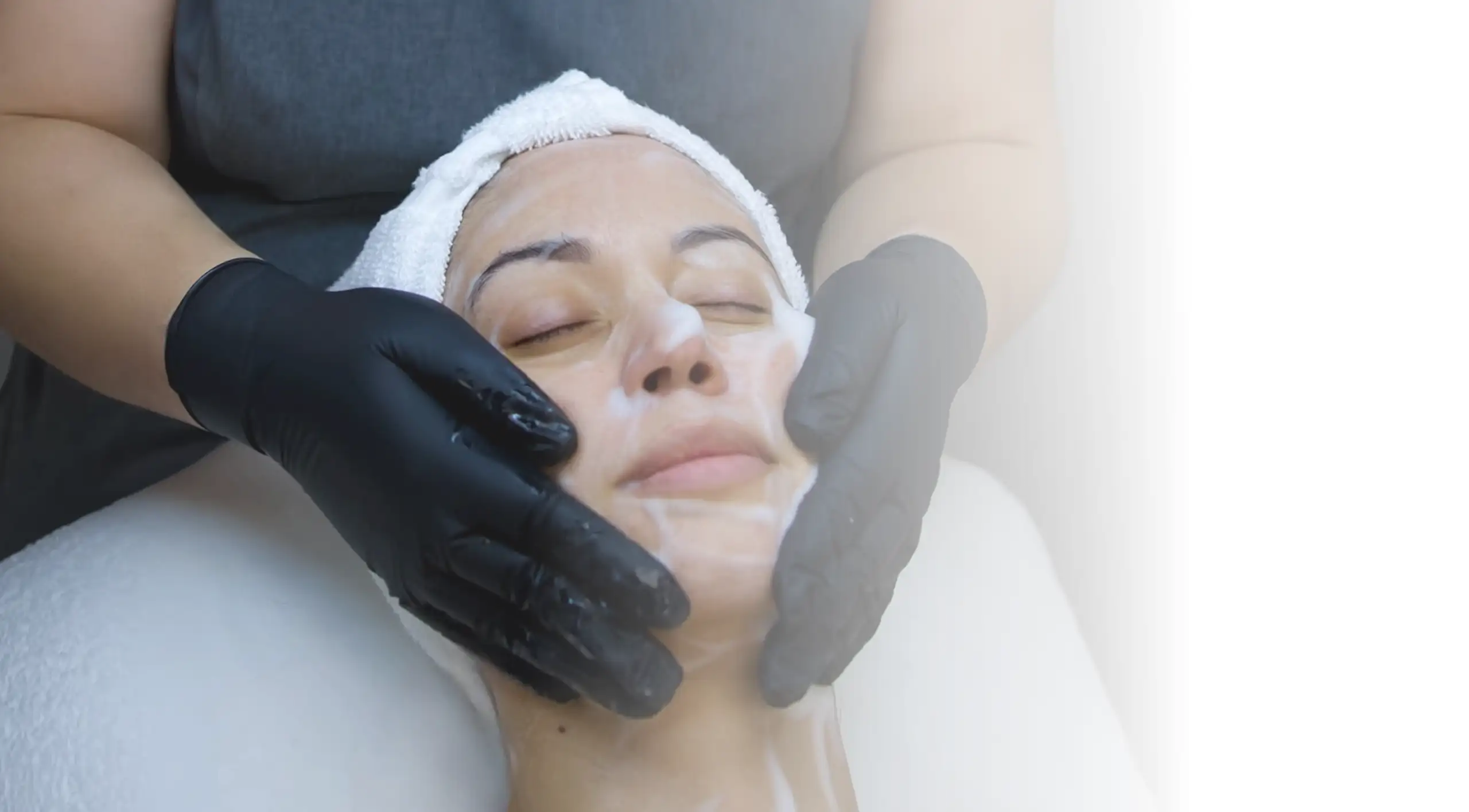 Paola massaging a client’s face during a facial.
