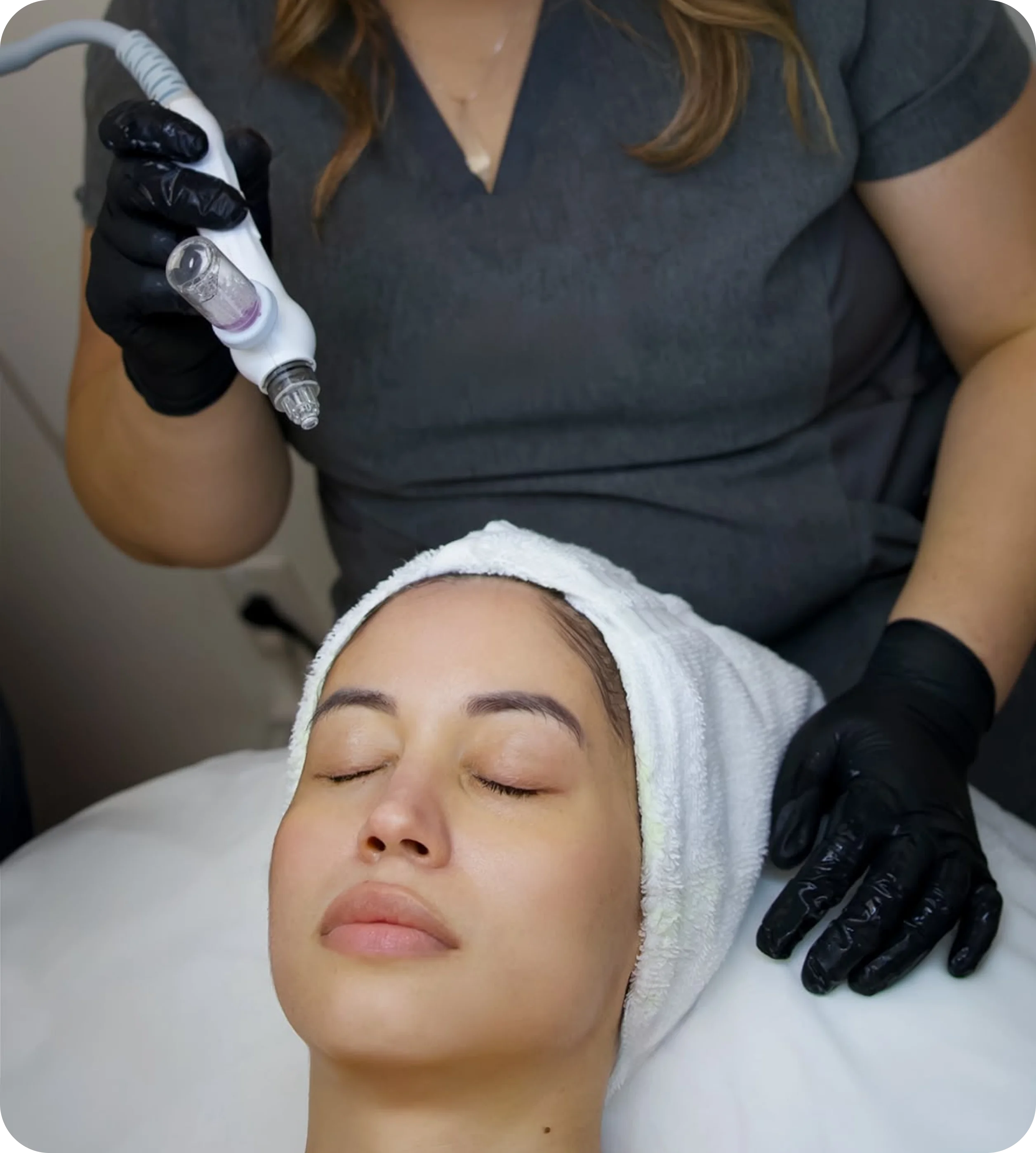 Paola performing a facial treatment with a device on a client.